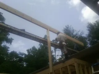 Carpenter setting a ridge beam over a new addition frame — Ice Dam Removal by Roofing Brothers in Crooks