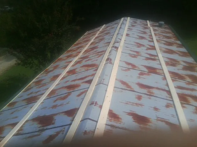 Rusted metal roof panels with new wood purlins before replacement — Storm Damage Roof Repair in Crooks by Roofing Brothers