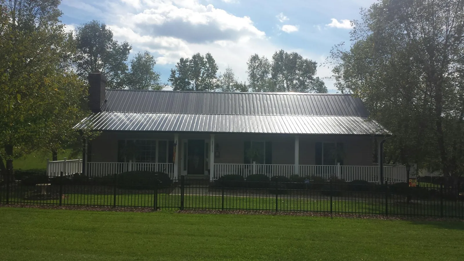Gray metal roof on a brick ranch with a full width front porch — Gutter Guard Installation work by our crew in Crooks