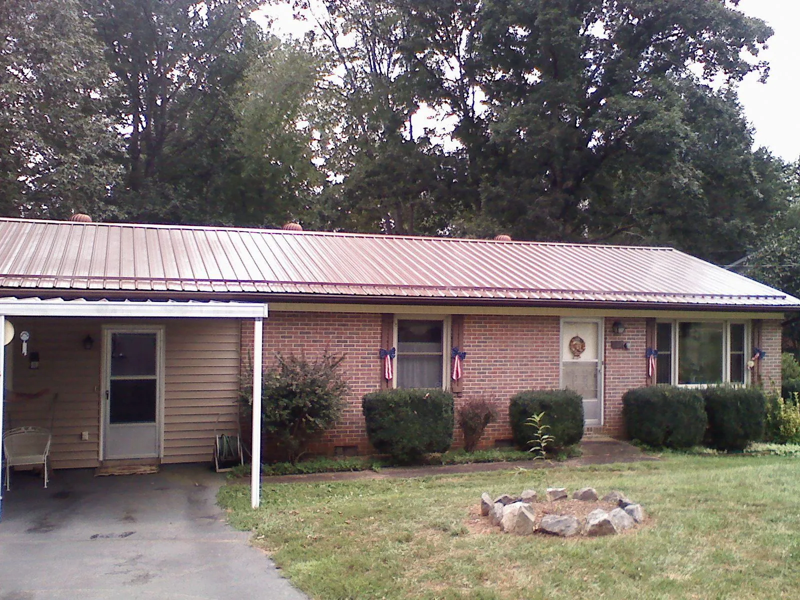 Bronze metal roof and carport on a brick ranch home — Roof Repair work by our crew in Crooks