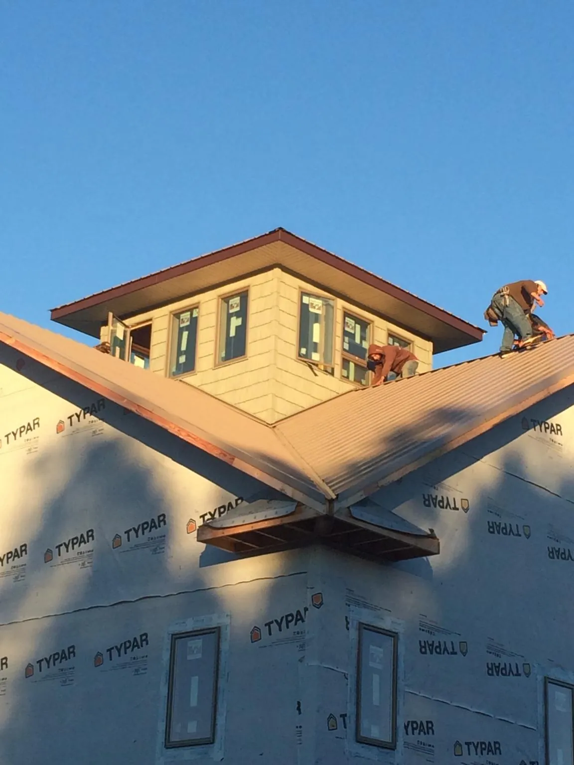 Roofers working around a rooftop cupola on a new metal roof at sunset — Roof Waterproofing in Crooks by Roofing Brothers